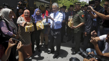Malaysia's King Sultan Abdullah Sultan Ahmad Shah, centre, hands out food parcels to journalists camped outside the palace following the resignation of Prime Minister Mahathir Mohamad in Kuala Lumpur on Tuesday.