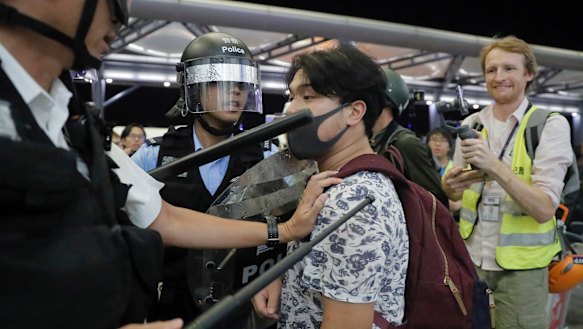 Police officers in riot gear arrest a protester at Hong Kong Airport.