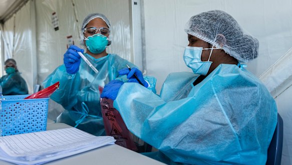 Nurses at a drive-through testing clinic in Castle Hill. NSW recorded seven cases of local transmission on Tuesday.