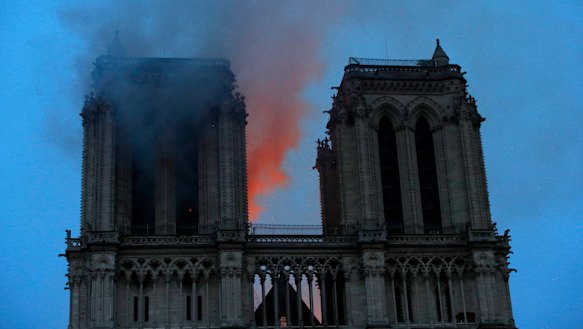 Smoke and flames fill the sky as a fire burns at the Notre-Dame Cathedral during a visit by French President Emmanuel Macron in Paris.