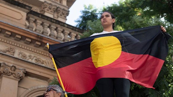 A protester holds an Aboriginal flag at a rally in Sydney to mark 30 years since the royal commission.