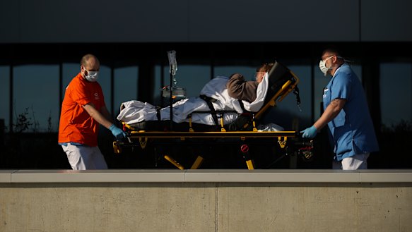 Hospital staff wearing face masks to protect against coronavirus, transfer a patient to MontLegia hospital in Liege, Belgium.
