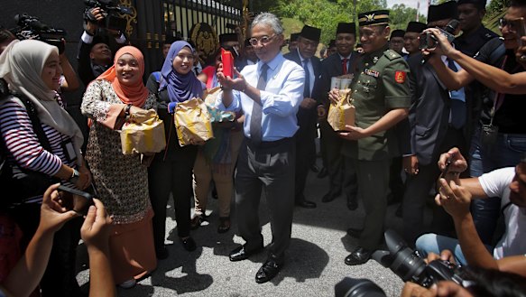 Malaysia's King Sultan Abdullah Sultan Ahmad Shah, centre, hands out food parcels to journalists camped outside the palace following the resignation of Prime Minister Mahathir Mohamad in Kuala Lumpur on Tuesday.