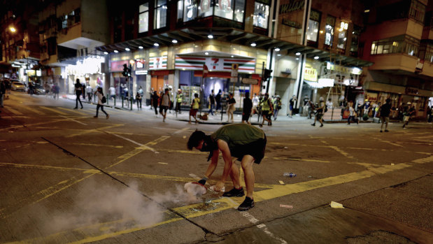 A protester uses a plate to cover a tear gas during clashes with policemen near the Shum Shui Po police station in Hong Kong.