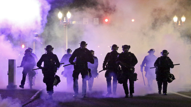 Police officers walk enveloped by tear gas in Portland, Oregon. 