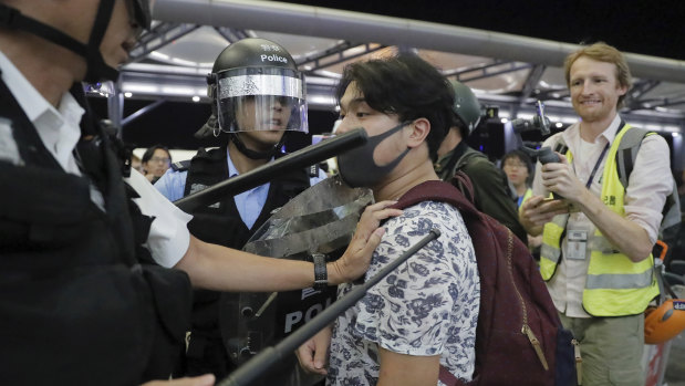Police officers in riot gear arrest a protester at Hong Kong Airport.