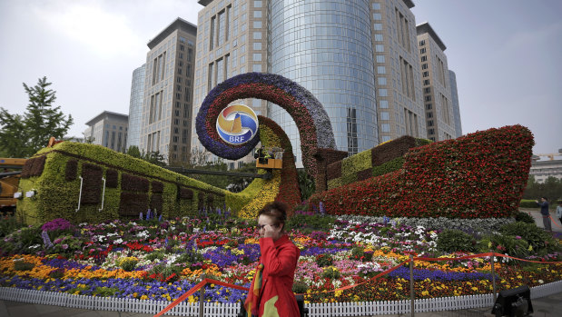 A woman walks by a display in the shape of a train and a container vessel for promoting the Belt and Road Forum in Beijing.