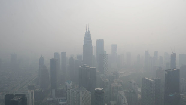 The Petronas Twin Towers, centre, and other buildings stand shrouded in haze in Kuala Lumpur, Malaysia.