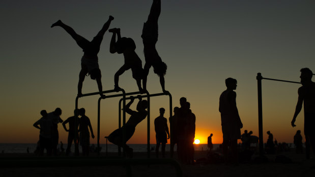 Men exercise in a public gym as the sun sets at the Victoria beach in Cadiz, Spain.