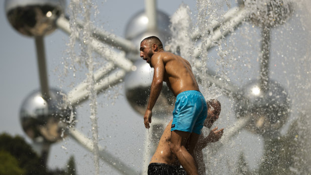 Two men cool off in a public fountain near the Atomium in Brussels on Wednesday.