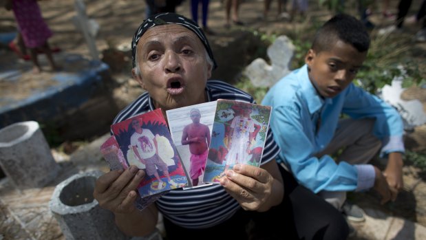 Yajaira Rojas shows photos of her late son Alix Eduardo Diaz during his funeral at the Municipal Cemetery of Valencia, Venezuela, on Friday.
