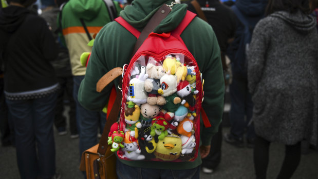 An attendee wears a backpack full of mascots at the Yuru-chara Grand Prix in Nagano, Japan.