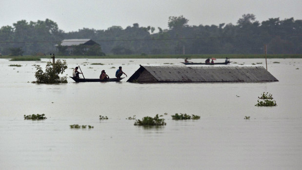 Flood affected villagers travel on boats near a submerged house in Burha Burhi village, east of Gauhati, India.