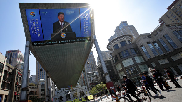 People pass by a TV screen broadcasting President Xi Jinping's opening speech, outside a shopping mall in Beijing. Xi promised to set high standards for China's Belt and Road infrastructure initiative, seeking to dispel claims that it is just a cloak for strategic expansion.