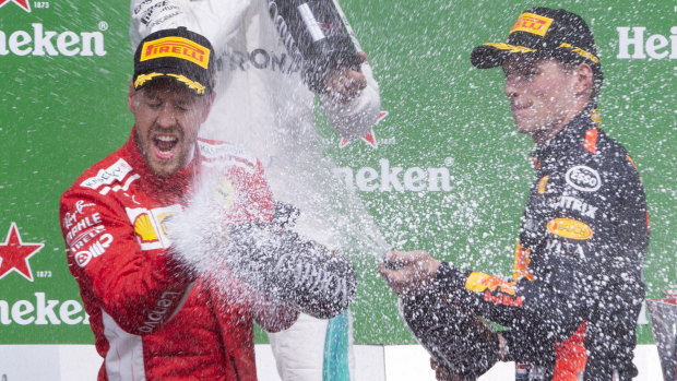 Race winner, Ferrari's Sebastian Vettel of Germany, left, is sprayed with champagne by third place finisher Red Bull's Max Verstappen.