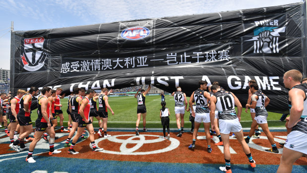 St Kilda and Port Adelaide players run through the banner before the match in Shanghai.