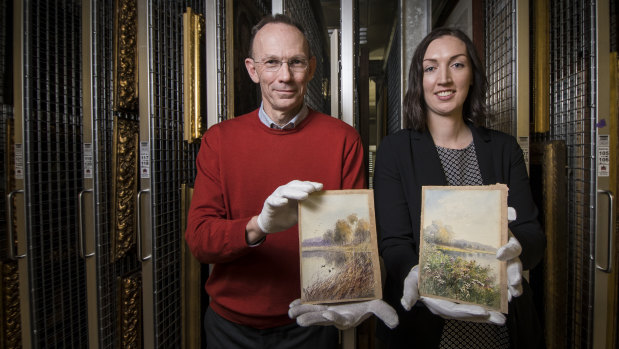 National Library of Australia acquisitions pictures branch, Mike Proud and pictures acquisition team leader, Roxi Ruuska hold two recently donated paintings by Marian Ellis Rowan which were found in an op shop. 