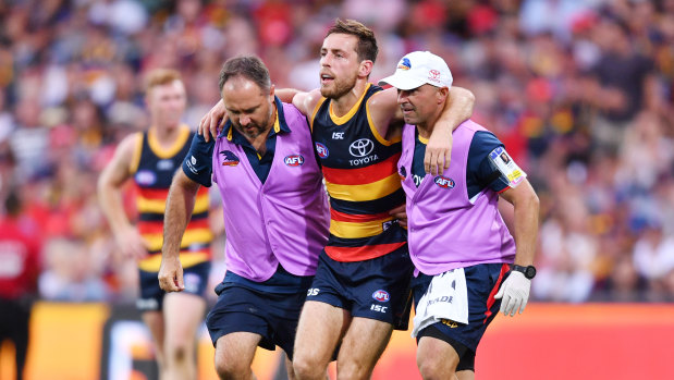Richard Douglas is helped off the field during the round one match between Adelaide and Hawthorn. 