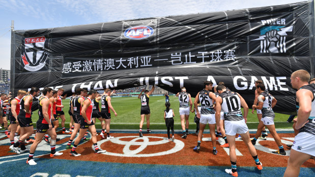 Breakthrough: St Kilda and Port Adelaide players run through the banner before the match at at Jiangwan Stadium in Shanghai.