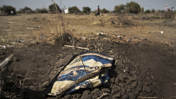 A small cross made of sticks and a religious blanket lie on top of the grave of a small child who was wounded during recent fighting between government and rebel forces in Bor but who died after fleeing by river barge across the Nile river to the town of Awerial, South Sudan.