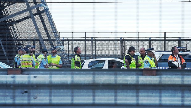Penalty: Police watch a man climbing Sydney Harbour Bridge, the fine for which will be increased.
