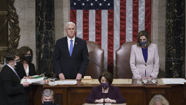 Former vice-president Mike Pence is pictured with Speaker of the House Nancy Pelosi just before being ushered out of the chamber on January 6.