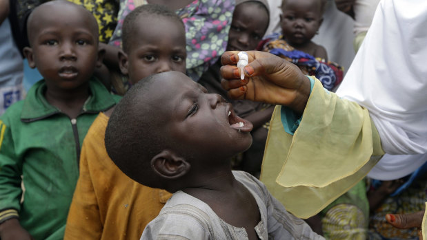 A health official administers a polio vaccine to children at a camp in Nigeria in 2016. Programs like these have stopped during the coronavirus pandemic.