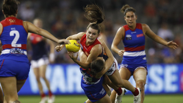Lily Mithen of the Demons is tackled by Bulldog Naomi Ferres. 
