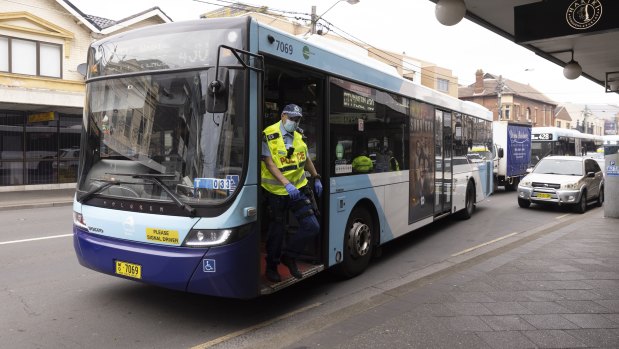 A police officer leaves a bus after checking the identification of passengers.
