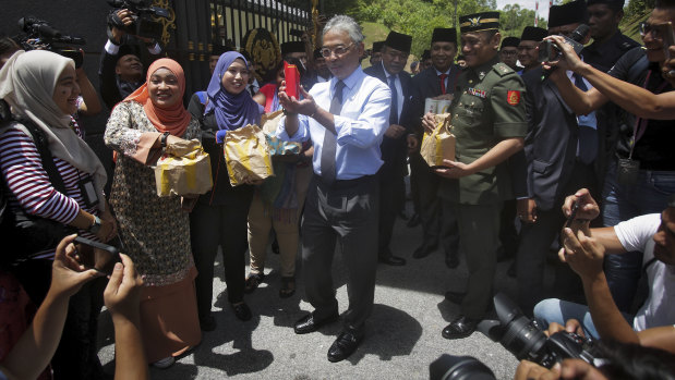 Malaysia's King Sultan Abdullah Sultan Ahmad Shah, centre, hands out food parcels to journalists camped outside the palace following the resignation of Prime Minister Mahathir Mohamad in Kuala Lumpur on Tuesday.