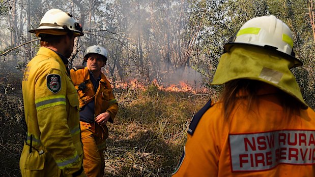 Captain Craig Byrne (centre) from the Grays Point Rural Fire Service and his crew monitor a fire in bushland in Menai on Sunday.