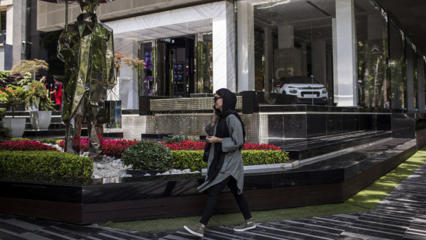 A woman passes by a showroom selling foreign cars in Tehran. Big European companies are weighing whether to rapidly end operations in Iran in line with US sanctions.