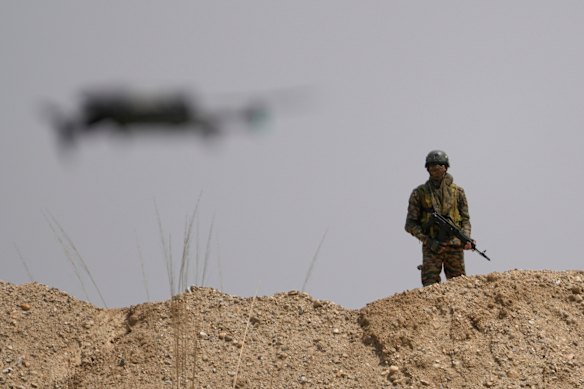 An Indian army soldier stands guard as a drone takes a flight during a military drill .