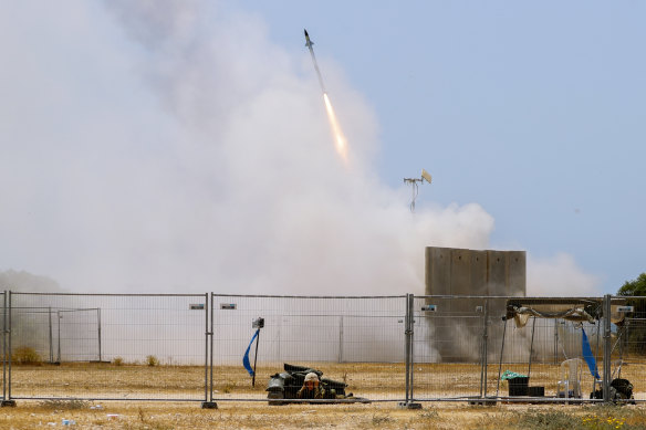 A Israeli soldier takes cover as an Iron Dome air defense system launches to intercept a rocket from the Gaza Strip, in Ashkelon in southern Israel.