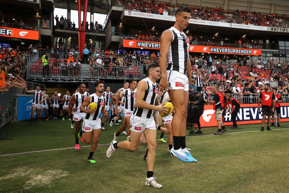 Nick Daicos, middle, leaps high as he runs out with Collingwood for opening round