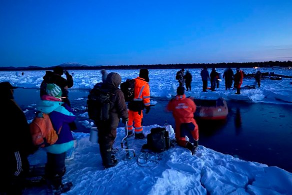 Rescuers in the foreground help a group of stranded fishermen.