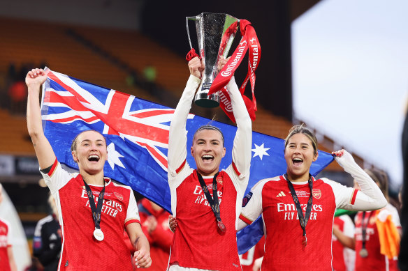 Matildas stars Caitlin Foord, Steph Catley and Kyra Cooney-Cross lift the League Cup they won at Arsenal in March.