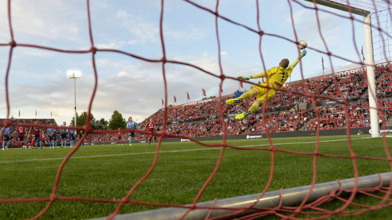 At full stretch: Sydney FC goalkeeper Andrew Redmayne tries to save a long-range Reds' effort.