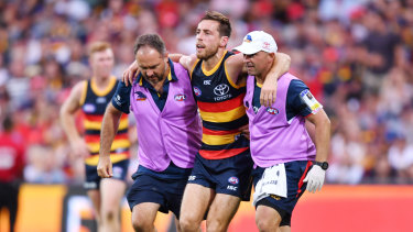 Richard Douglas is helped off the field during the round one match between Adelaide and Hawthorn. 