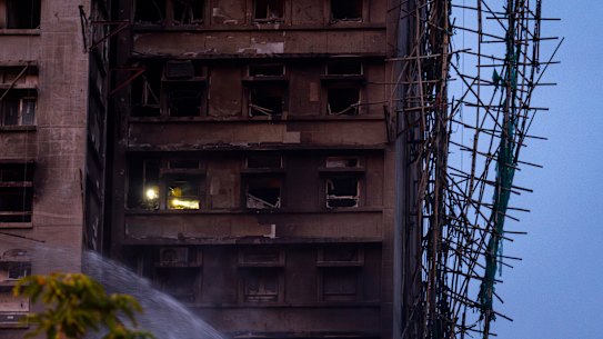 Firefighters with flashlights search for survivors inside a burned building at Wang Fuk Court.