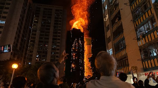 Bystanders look on as flames engulf the buildings.