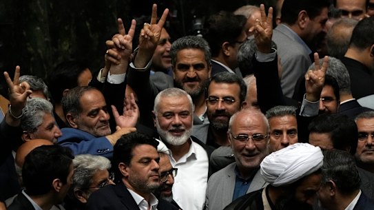 Hamas chief Ismail Haniyeh, centre, flashes a victory sign as he is surrounded by a group of Iranian MPs after the conclusion of the swearing-in ceremony of newly-elected Iranian President Masoud Pezeshkian.
