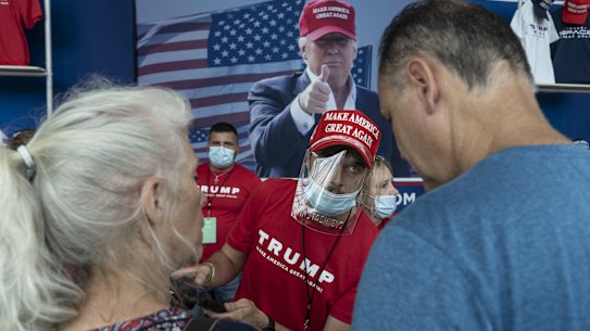 A vendor wearing a protective mask and shield speaks with customers ahead of Trump's rally in Tulsa.