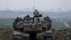 Israeli soldiers sit on a tank as it takes position in front of the northern Gaza Strip.
