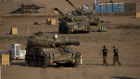 Israeli soldiers walk by artillery units near the border with the Gaza Strip.