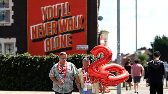 Fans of Liverpool, wearing scarfs featuring Diogo Jota and carrying balloons which spell out “20” make their way to the stadium as a mural which reads “You’ll Never Walk Alone” can be seen as tributes are laid for Diogo Jota at Anfield on July 03, 2025 in Liverpool, England. The current Liverpool player and Portugal international Jota died in a car crash in Zamora, Spain at the age of 28