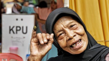 Umi, a rubbish picker from a rural slum in Kali Baru village, North Jakarta, shows her inked finger after casting her vote.