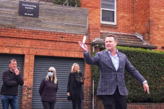 Auctioneer Josh Stirling accepts bids for a property on Brighton Road, St Kilda on Sunday. The two-bedroom apartment sold for $891,000, which was $100,000 above reserve.