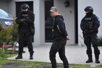 A man paces outside the Keilor Lodge home as police raid the property.