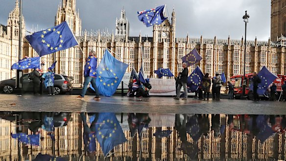 Protesters are reflected in a puddle as they wave European Union flags to demonstrate against Brexit in front of Parliament in London on Monday.